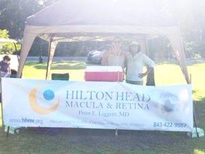 Two women pose under a tent on a hot summer day during a golf tournament.