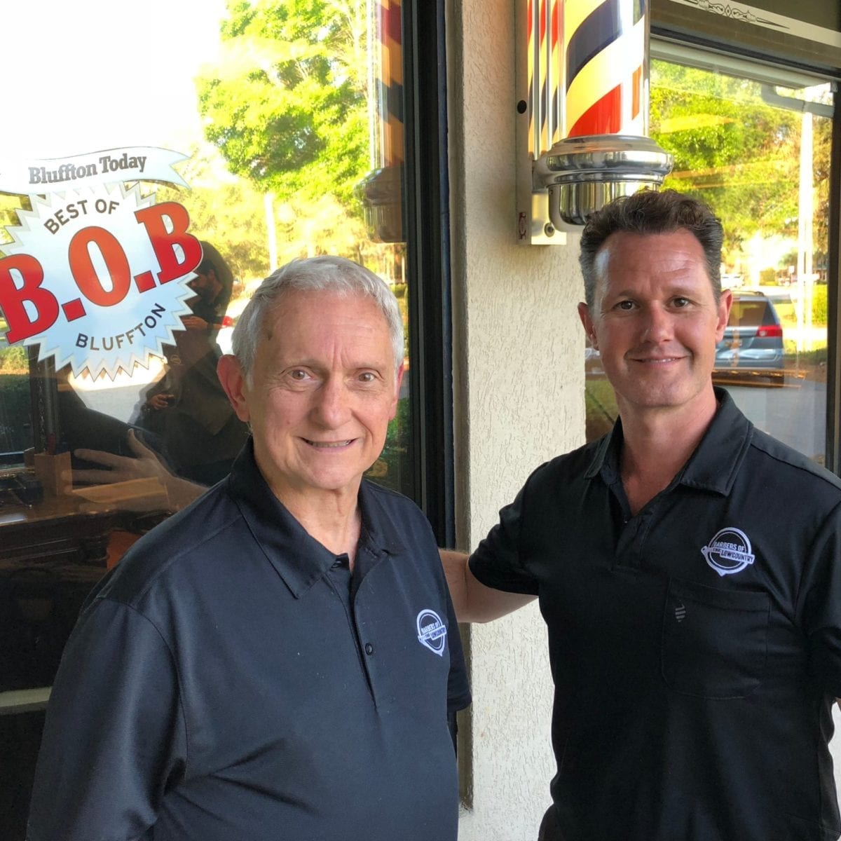Lou Nelsen and Brent Nelsen pose in front of their barber pole at the Barbers of the Lowcountry shop located in Bluffton SC