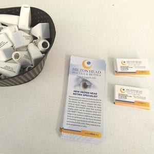 4x9 Rack Cards for Hilton Head Macular & Retina lay on a table next to business cards