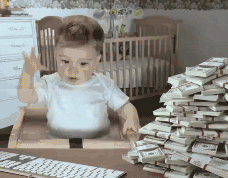 A baby sits in font of a computer and grabs at a pile of cash illustrating that an inbound marketing website saves money over time and helps make money