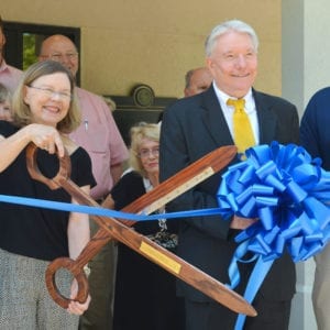 Dr. Peter Liggett and his wife Jean Collins use giant ceremonial scissors to cute the ribbon at their practice.