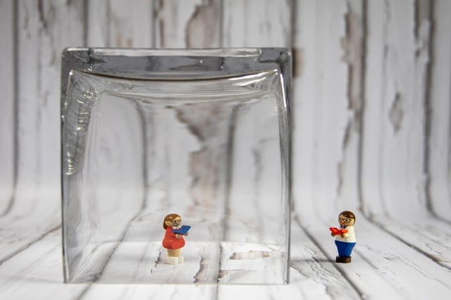Two computer-working LEGO figurines separated by a glass